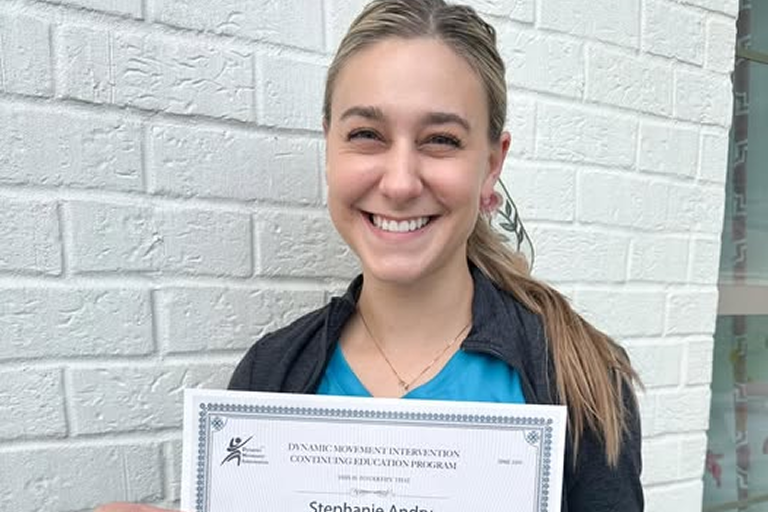 Paige Machen holding a physical therapy certification at Pediatric Therapy Solutions.